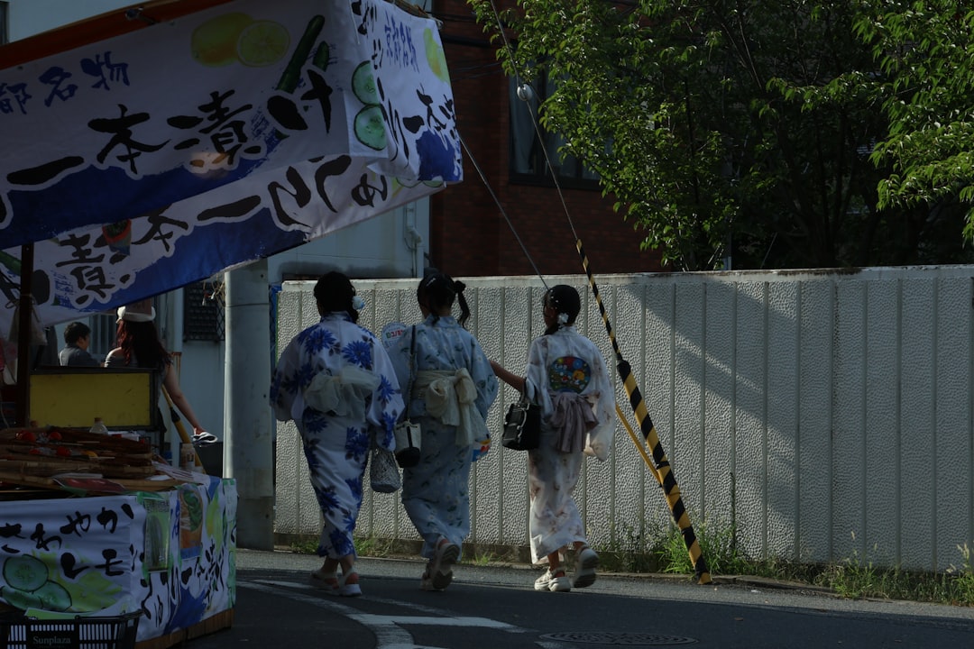 Three people in yukatas walking down a street