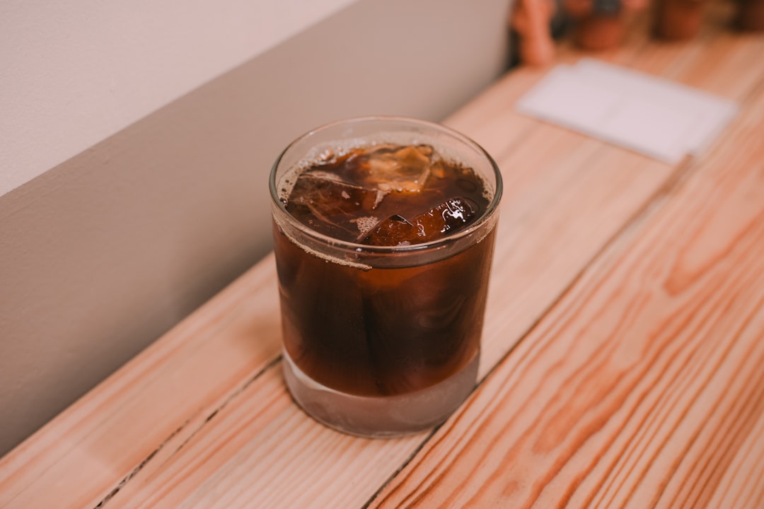 A glass of iced coffee on a wooden surface.
