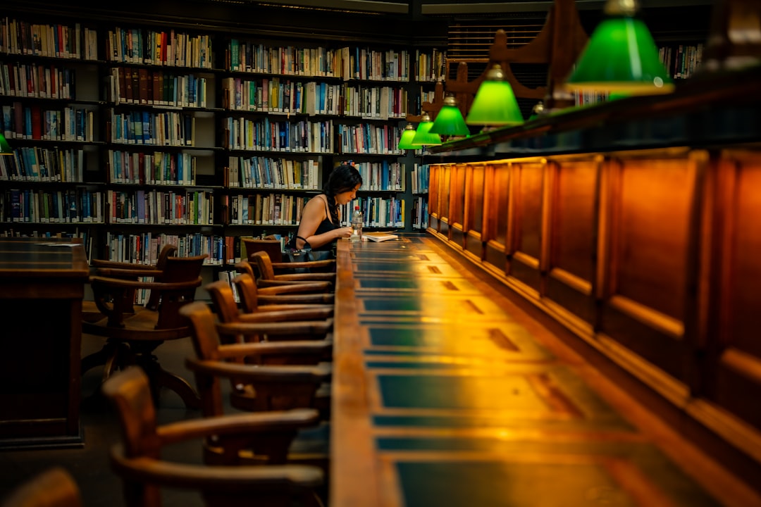 A woman reads at a long desk in a library.
