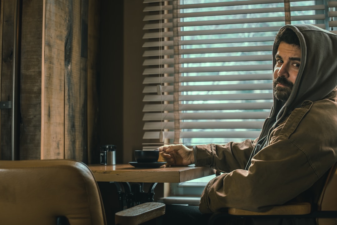 Man in hoodie holding coffee cup at table