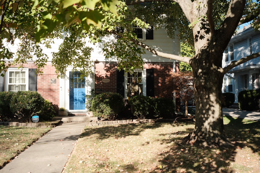A suburban house with a blue door and trees.